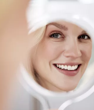 Woman admiring her whitened teeth in a mirror